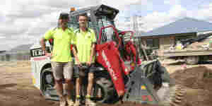 TL6R-Earthworm-SM-8023-8-LR-Web Red Takeuchi mini excavator in construction site with workers and equipment.
